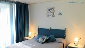 A bedroom with a bed, two bedside tables, a lamp, a wall decoration, and a window with curtains. - Scaglieri Mare - ibookingelba.com (Portoferraio)