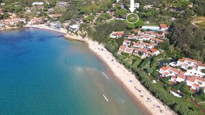 An aerial view of a coastal area with a beach, houses, and a pool. - Scaglieri Mare - ibookingelba.com (Portoferraio)