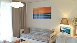 A cozy room with a bed, a table, a lamp, and a painting of a sunset over the ocean. - Scaglieri Mare - ibookingelba.com (Portoferraio)