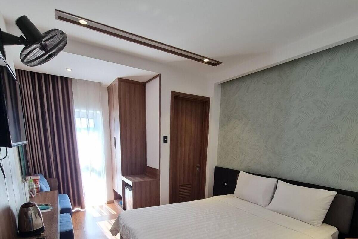 A modern hotel room with a large bed, a desk, a chair, and a television.
