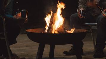 A group of people seated around a central fire pit.