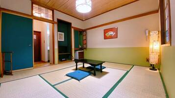 Una habitación con esteras de tatami, una mesa baja y cojines, vigas de madera en el techo y un farol japonés tradicional de papel.