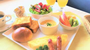 A breakfast plate with toast, sausages, scrambled eggs, a bowl of soup, a salad, and a bowl of fruit.