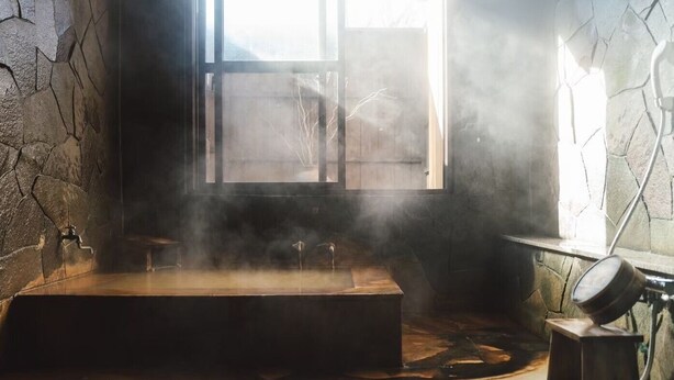 A steam room with stone walls, a wooden bench, and a stone floor. - Lodge Atelier (Hokuto)
