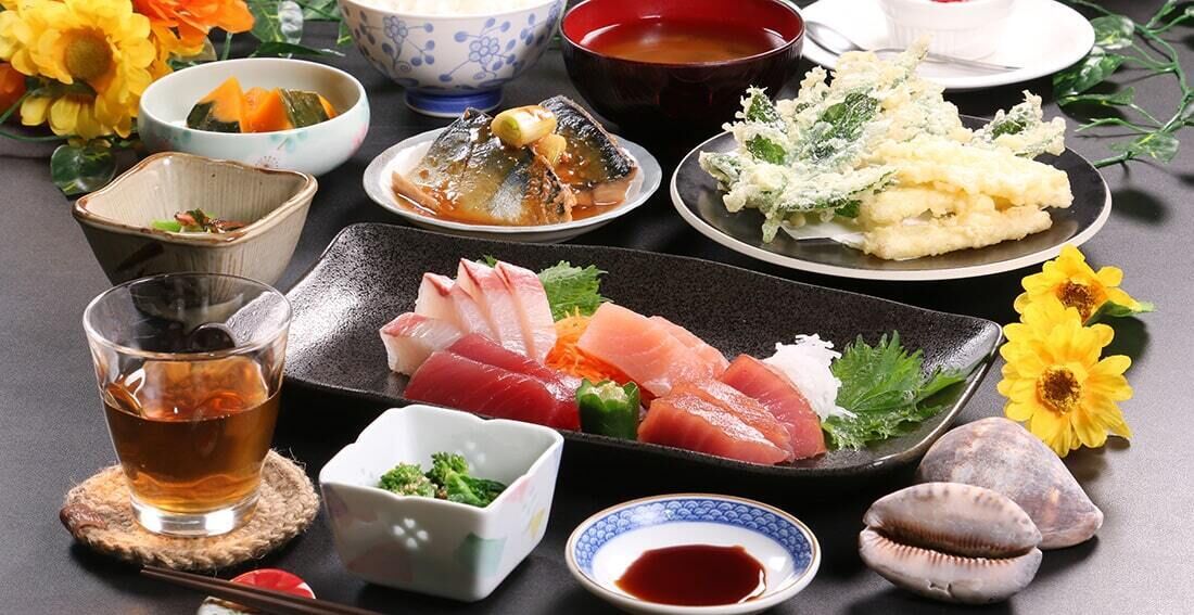 Verschiedene japanische Gerichte, darunter Sashimi, Tempura und eine Suppenschüssel.