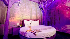 Un dormitorio con cama, mesita de noche y ventana.