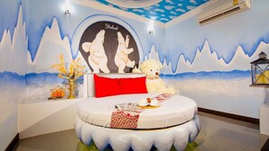 Un dormitorio con cama redonda, un mural en la pared y un plafón con lámpara.