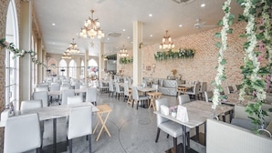 Un restaurante espacioso con techos altos, candelabros y paredes de ladrillo. Mesas y sillas dispuestas para comer.