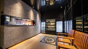 A modern interior with a brick wall, a counter with a sign, refrigerated display cases, and wooden seating.