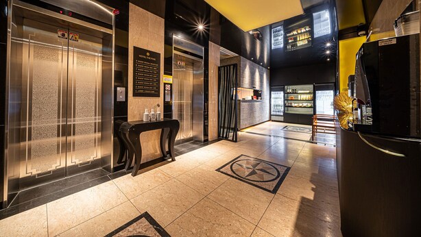 A hotel lobby with two elevators, a reception desk, and a minibar.