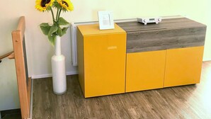 Una zona de recepción con un escritorio de madera, un jarrón con girasoles y un cuadro en el escritorio.