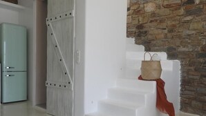 Un escalier à la finition blanche, un mur en pierre rustique et un réfrigérateur de style vintage.