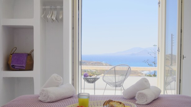 Un balcon avec une table préparée pour le petit-déjeuner, des serviettes et une vue sur la mer.