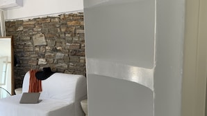Un salon moderne avec un mur en pierre, un canapé blanc et un ordinateur portable posé sur le canapé.