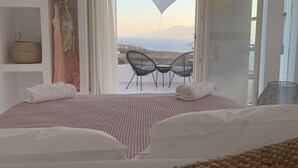 Une chambre avec un lit, une vue sur la mer et un balcon équipé de chaises.