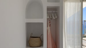 Une pièce avec un mur blanc, un panier en osier, une robe rose et une fenêtre ornée de rideaux légers.