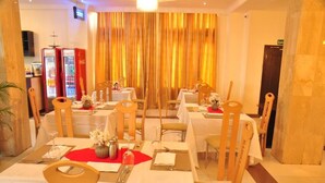 A dining area with tables set for four, each with white tablecloths, red placemats, and wooden chairs. - Demiral Hotel at The Place Lekki (Lekki)