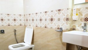 A bathroom with a toilet, a sink, and a shower. - Hexa Royal Elite (Mumbai)