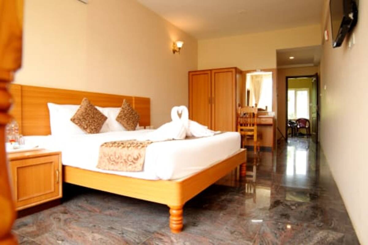 A hotel room with a wooden bed, a nightstand, a wardrobe, and a bathroom visible through an open door.