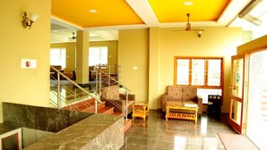 A spacious living area with a staircase, a sofa, and a coffee table. - Ack Palacce Inn (Yercaud)