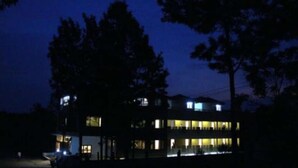 A multi-story building with illuminated windows and a visible entrance. - Ack Palacce Inn (Yercaud)