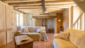 A rustic interior with exposed wooden beams, stone walls, and a cozy seating area with two sofas and a wooden table. - Dreamy Retreat in Loubejac (Loubejac)