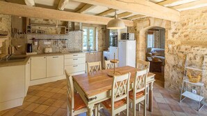 A rustic kitchen with exposed wooden beams, a tiled floor, and a dining area with a wooden table and chairs. - Dreamy Retreat in Loubejac (Loubejac)