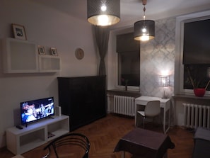 Relax in this stylish living room with a large window offering a view of the outside, a comfortable sofa, and a dining area with a table and chair.