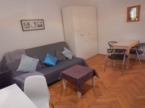 Cozy living space with a sofa, table, chair, and wardrobe.