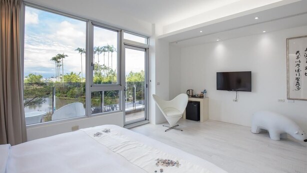 A modern hotel room with a large bed, a desk, a chair, a TV, and a polar bear sculpture. - WMS Villa (Sanxing)