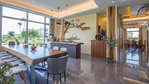 A spacious kitchen with a long wooden table and chairs, a built-in island, and a view of the outdoors. - WMS Villa (Sanxing)