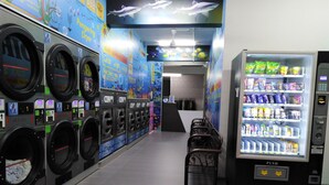 Eine Waschsalon mit mehreren Waschmaschinen und einem Getränkeautomaten.