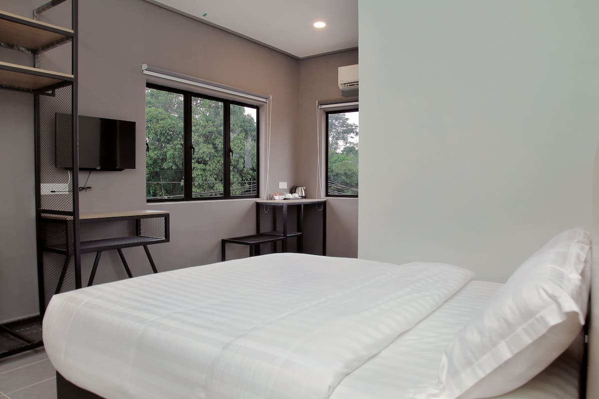 Un dormitorio moderno con una cama grande, un escritorio y un televisor.