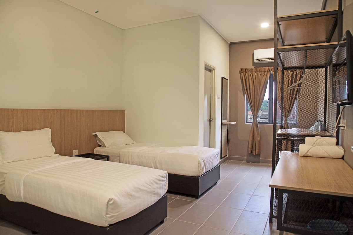 Habitación de hotel con dos camas, un escritorio y una ventana con cortinas.