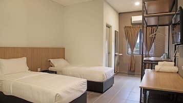A hotel room with two beds, a desk, and a window with curtains.