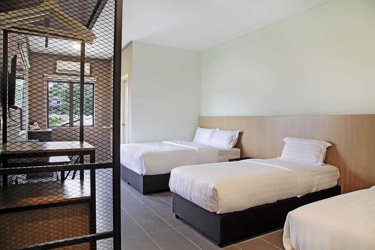 Habitación de hotel con dos camas, una mesita y vistas al exterior.