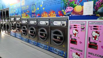 A row of self-service laundry machines with a colorful underwater mural in the background.