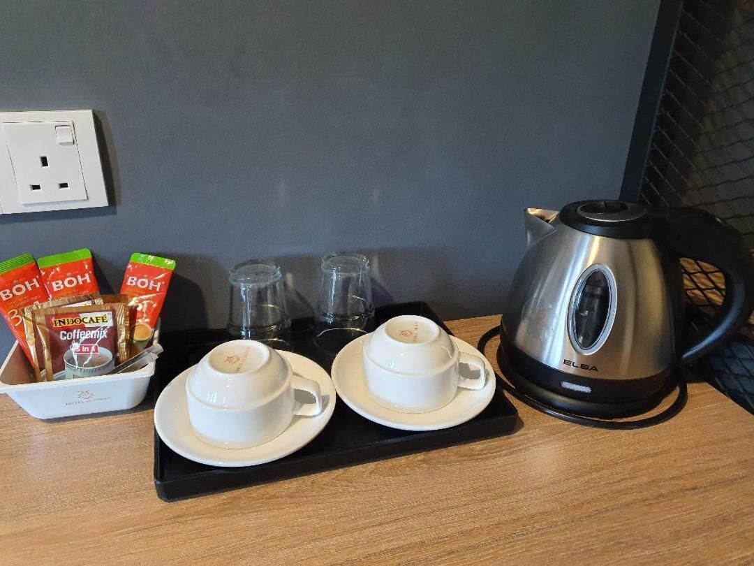 A breakfast setup with two white cups and saucers, a black tray, a glass pitcher, and packets of coffee and tea.
