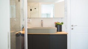 Un baño moderno con un lavamanos grande, un espejo y una planta en maceta.
