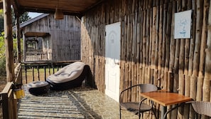 Um quarto rústico de madeira com uma cadeira estofada, uma mesa pequena e uma porta com o número 32.