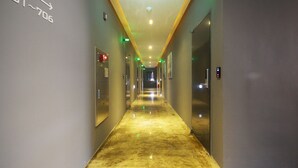 Un pasillo largo y estrecho con suelo reflectante y puertas a ambos lados.