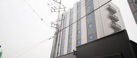 A multi-story building with a parking sign, a garage door, and visible electrical infrastructure.
