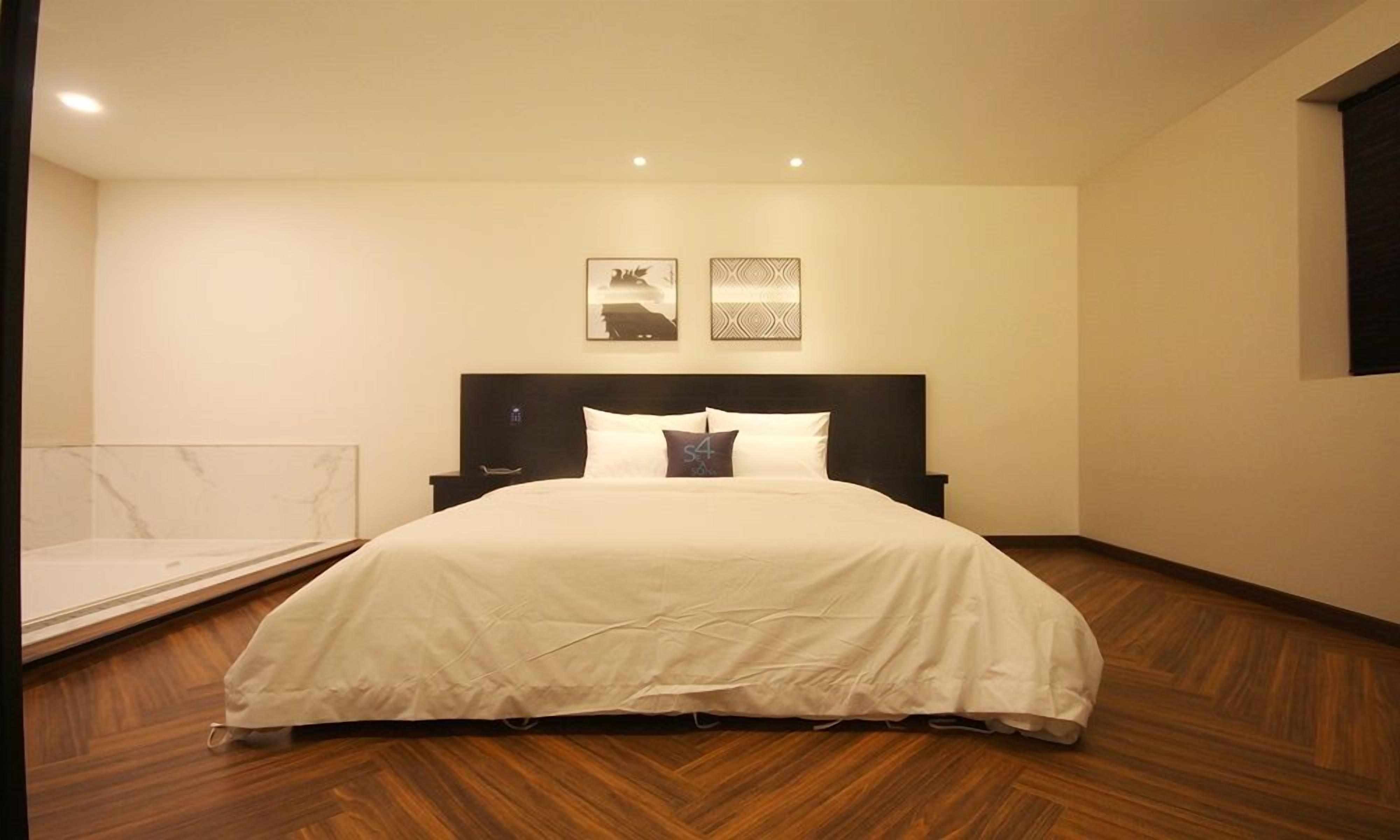 A bedroom with a bed, a headboard, and two wall-mounted artworks.