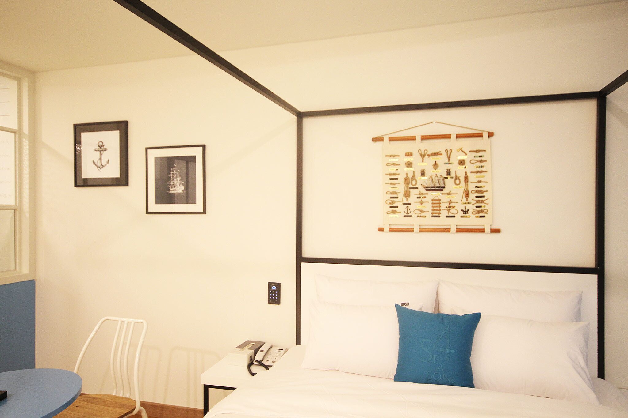 A hotel room with a bed, a desk, and a chair. There are framed pictures on the wall.