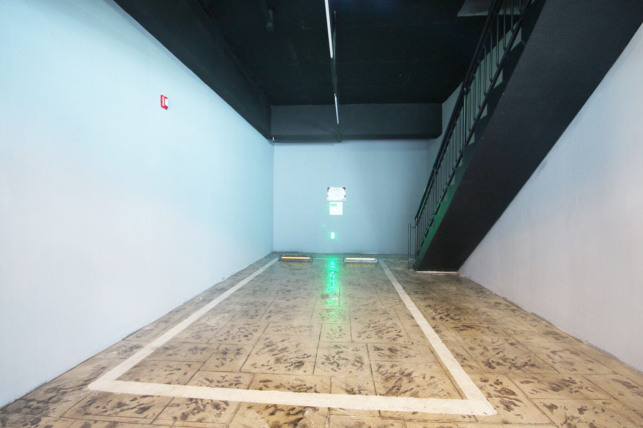 A spacious indoor area with a tiled floor, a staircase on the right, and a light-colored wall.