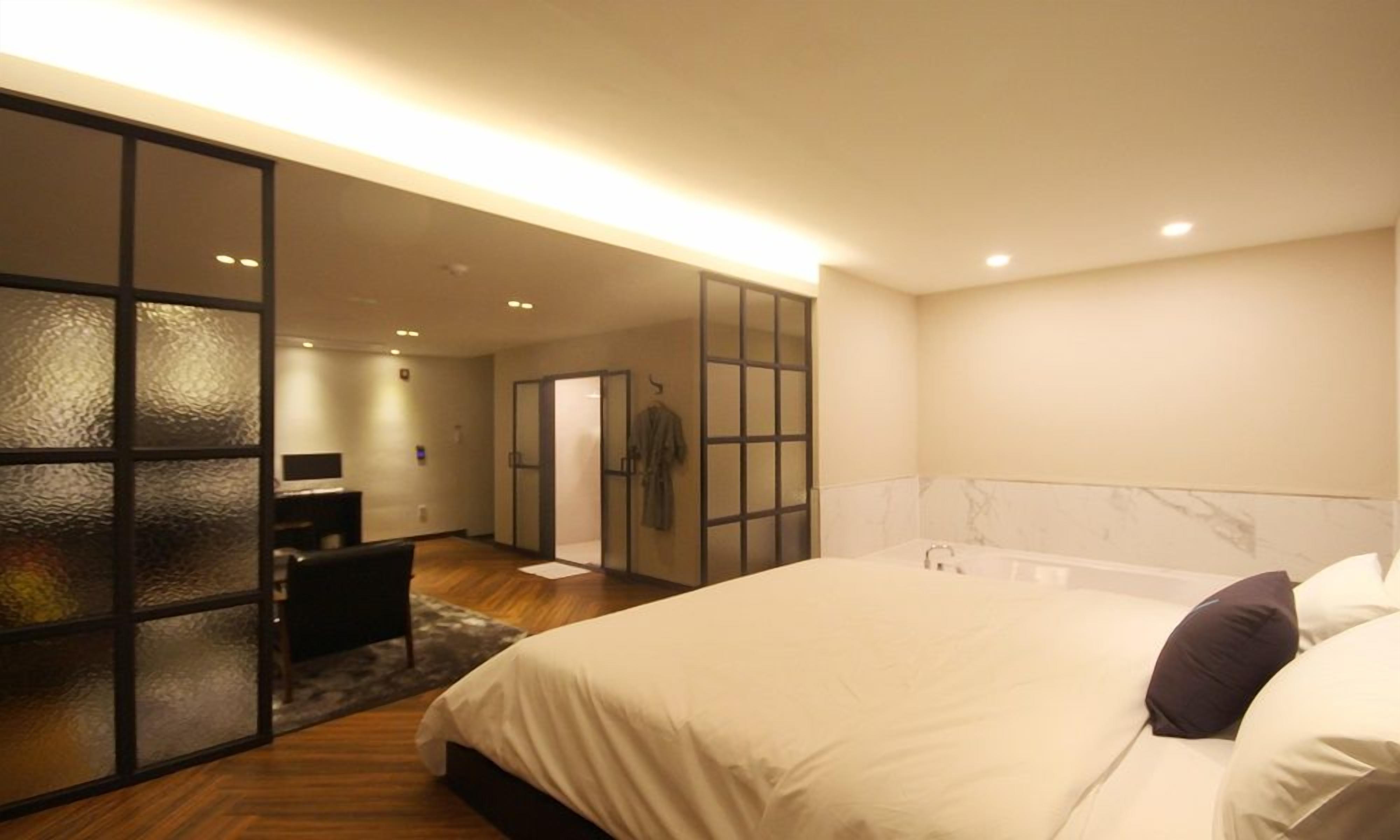 Un dormitorio moderno con una cama grande, un vestidor y un baño con pared de mármol.