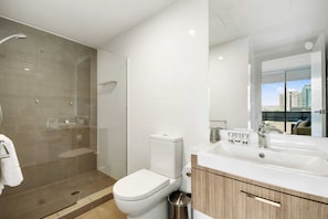 A modern bathroom with a glass-enclosed shower, a toilet, and a sink with a mirror above it.