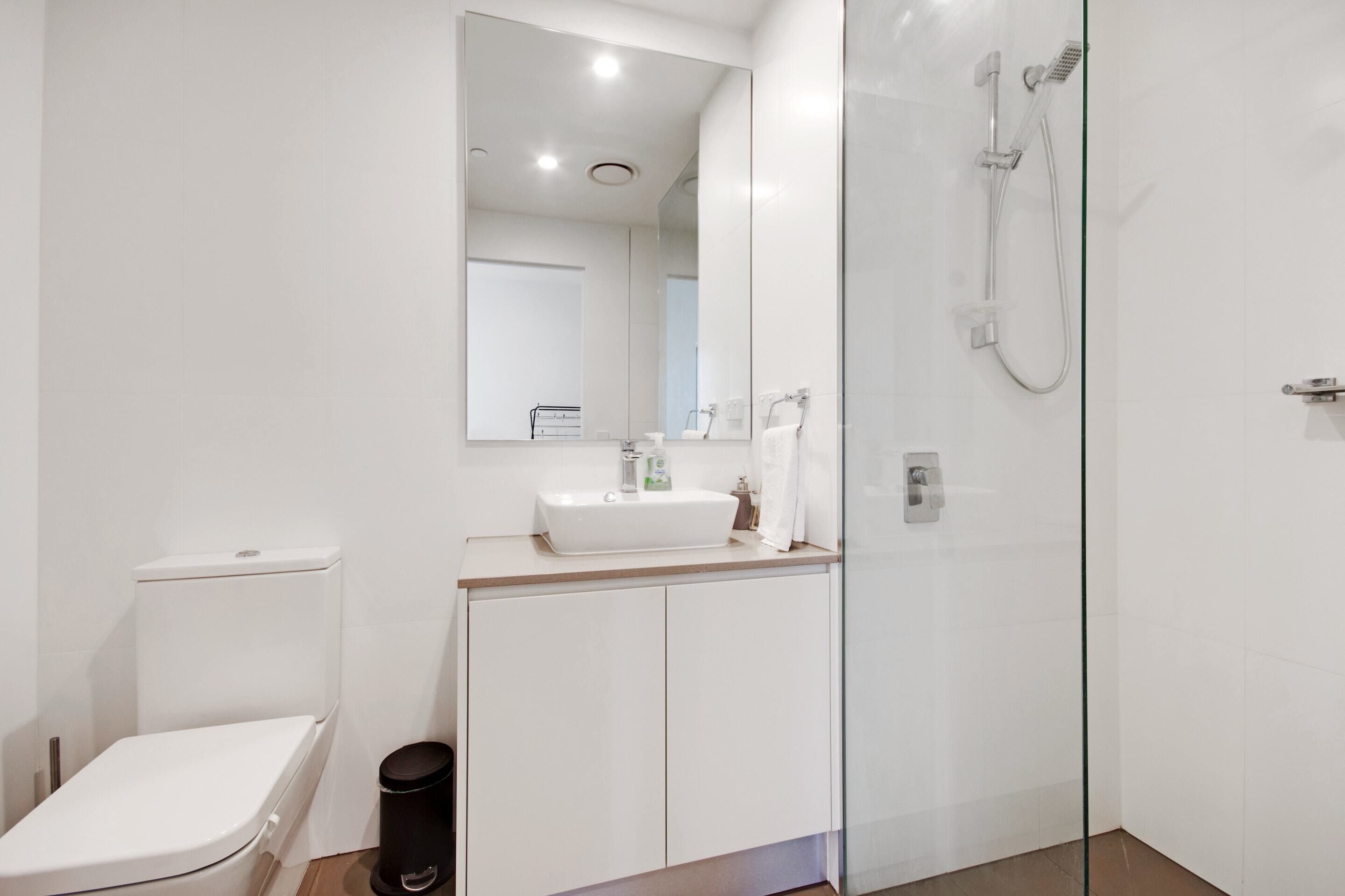 A modern bathroom with a toilet, sink, and glass-enclosed shower.