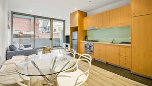 Een moderne keuken met houten kastjes, een glazen eettafel en uitzicht op buiten.