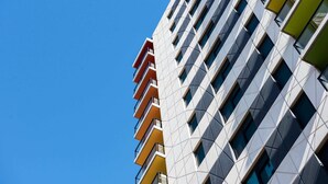 A modern building with a geometric facade, multiple balconies, and a clear blue sky in the background. - Swainson on Synagogue (Adelaide)